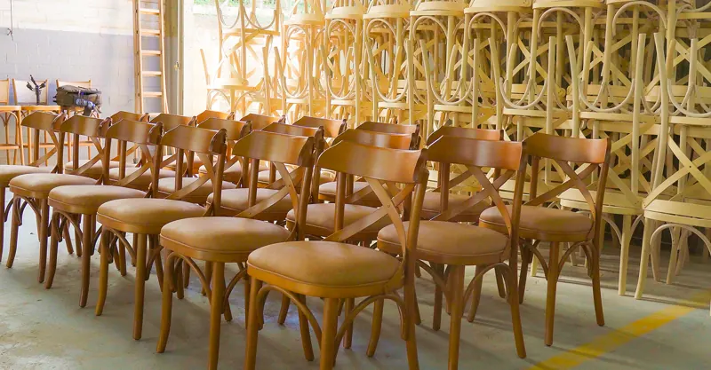 Fileiras de Cadeiras X prontas, com estruturas cruas empilhadas até o teto
